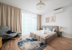 A modern bedroom with a bed, a chair, a round rug, and artwork on the wall. - Browary Warszawskie Signature Studio (Warszawa)