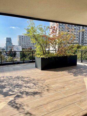 A balcony with a large planter, a view of a cityscape, and a tiled floor. - Grzybowska 37 Designer Apartment (Wola)