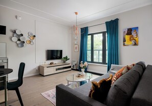 Una sala moderna con televisor de pantalla plana, un sofá, una mesa de centro y un comedor con una silla y una mesa.