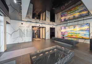 A modern lobby with marble walls, a central seating area, and a large abstract painting. - Grzybowska Designer Apartment (Wola)
