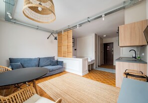 A modern living room with a sofa, a dining table, and a kitchen area. - Solec Powiśle Harmony Studio (Warszawa)