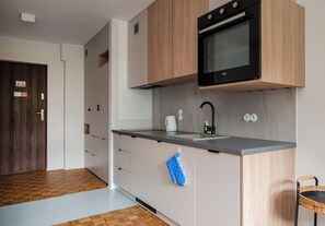 A modern kitchen with a built-in oven, a sink, and a countertop. - Solec Powiśle Harmony Studio (Warszawa)