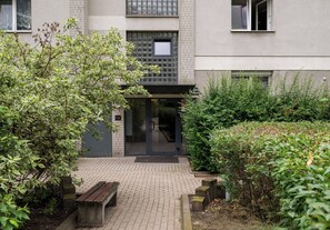 A building entrance with a glass door, a bench, and a paved walkway. - Solec Powiśle Harmony Studio (Warszawa)
