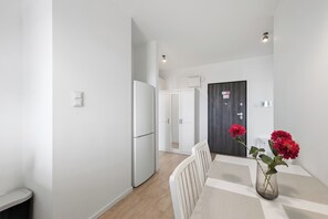 A modern kitchen with white cabinetry and a dark wood door. - Północna White Elegance Apartment (Lublin)