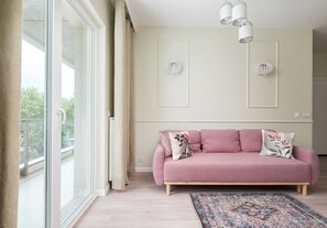 A modern living room with a pink sofa, a patterned rug, and a large window with curtains. - Westfield Mokotów Modern Apartment (Warszawa)