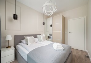 A modern bedroom with a bed, bedside tables, a mirror, and a door. - Westfield Mokotów Modern Apartment (Warszawa)