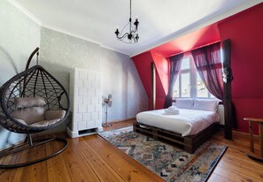 A bedroom with a hanging chair, a bed, a radiator, and a window with curtains. - Kopernika Old Town Homely Apartment (Poznań)