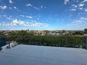 A rooftop terrace with a view of a cityscape, a metal railing, and a clear sky. - Spacious 4Bed Room Home with Sunroom, All Utilities Included & Parking Available (San Diego)