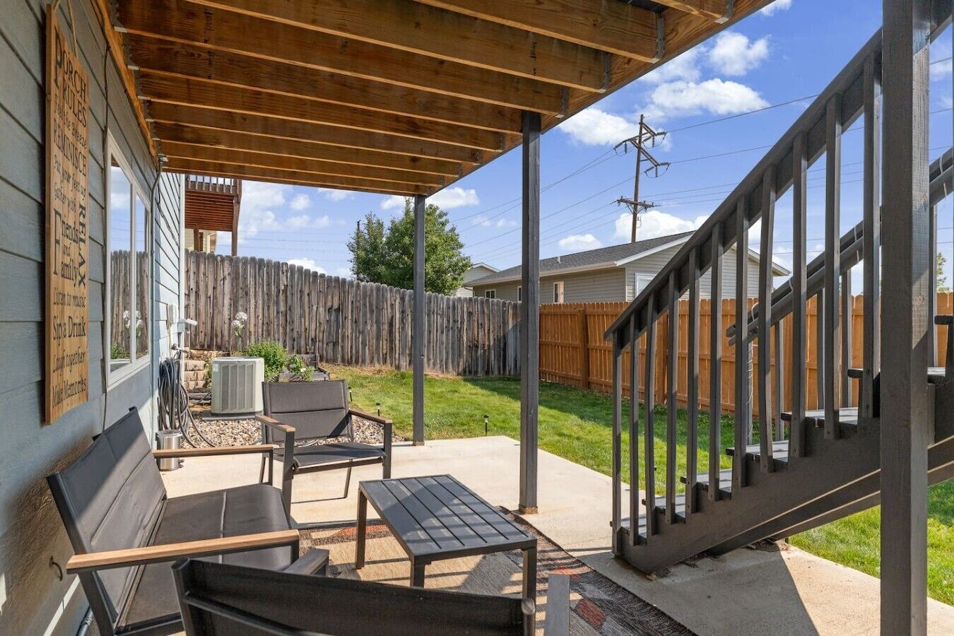 A covered patio area with outdoor furniture, a wooden fence, and a view of the backyard.