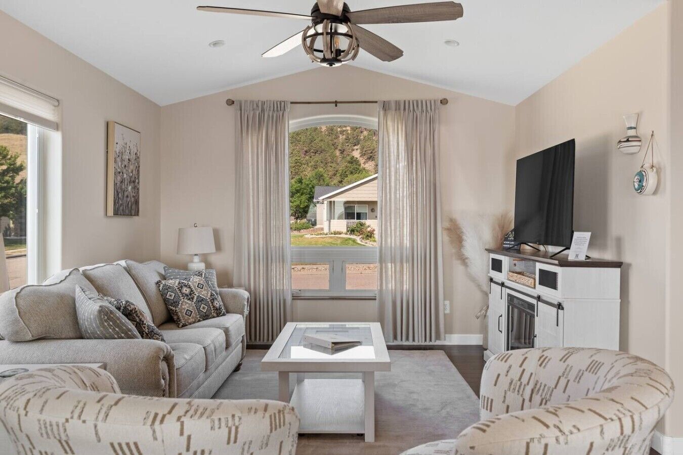 A living room with a sofa, armchairs, a coffee table, a TV, and a cabinet.