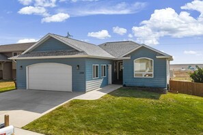Einbungalow mit Garage und Veranda, bewölkter Himmel.
