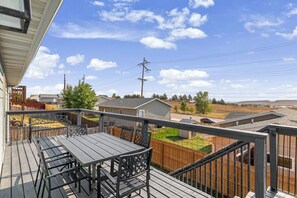Eine Terrasse mit Tisch und Stühlen, die auf ein Wohngebiet mit Häusern und einem klaren Himmel blickt.