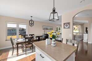 A modern kitchen with a central island, dining area, and a view of the neighborhood.