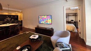 A modern living room with a dining area, a flat-screen TV mounted on the wall, and a cozy seating arrangement. - Designer 1685 SF Penthouse, plus huge 650 SF terrace, looks to Trinity Church (New York)