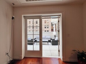 Habitació amb porta corredissa de vidre que dona a una zona d'estar exterior amb sofà i taula.