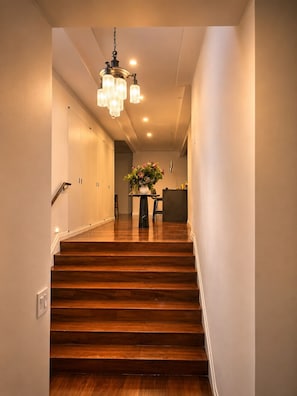 A wooden staircase leading to a room with a chandelier and a vase of flowers. - Designer 1685 SF Penthouse, plus huge 650 SF terrace, looks to Trinity Church (New York)