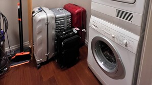 A laundry area with a washing machine and a drying rack. There are suitcases and a vacuum cleaner. - Designer 1685 SF Penthouse, plus huge 650 SF terrace, looks to Trinity Church (New York)