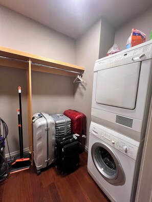 A laundry area with a washing machine and a drying rack. There are suitcases and a vacuum cleaner. - Designer 1685 SF Penthouse, plus huge 650 SF terrace, looks to Trinity Church (New York)