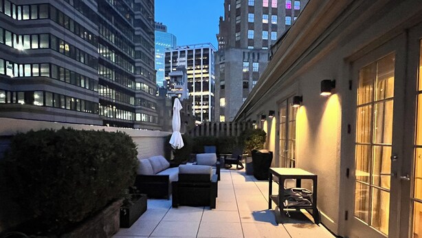 A rooftop terrace with outdoor seating, a hedge, and a view of surrounding buildings. - Designer 1685 SF Penthouse, plus huge 650 SF terrace, looks to Trinity Church (New York)