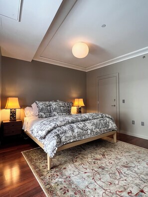A bedroom with a bed, two bedside lamps, a door, and a patterned rug. - Designer 1685 SF Penthouse, plus huge 650 SF terrace, looks to Trinity Church (New York)