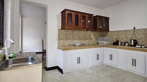 A kitchen with white cabinets, a stainless steel sink, and a patterned backsplash. - The ritz villa Nuwaraeliya (Nuwara Eliya)