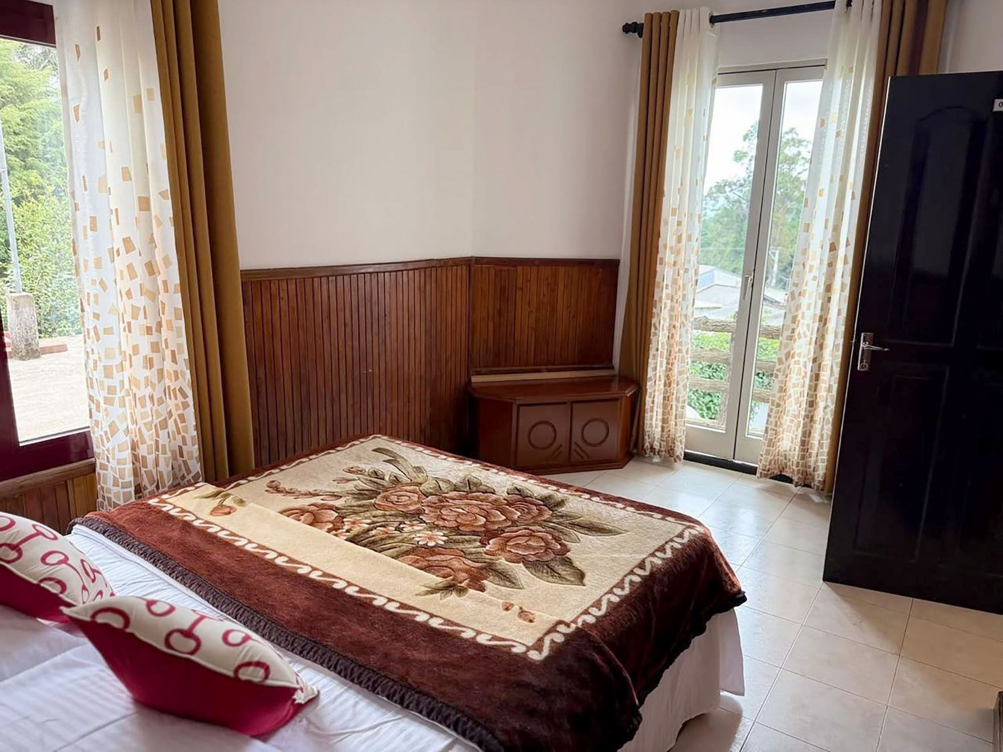 A bedroom with a bed, a wooden headboard, a nightstand, and a door leading to an outdoor area.