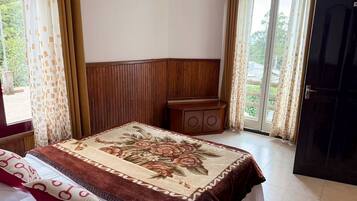 A bedroom with a bed, a wooden headboard, a nightstand, and a door leading to an outdoor area.