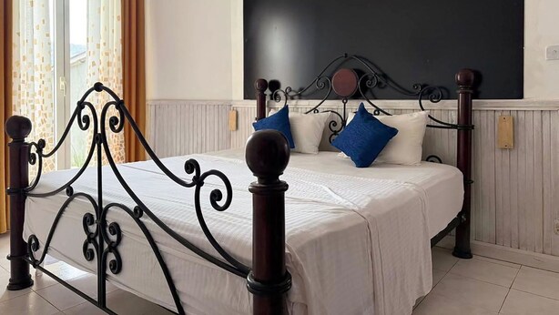 A bedroom with a bed, curtains, a blackboard on the wall, and a window with a view. - The ritz villa Nuwaraeliya (Nuwara Eliya)