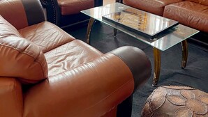 A living room with leather sofas, a glass coffee table, and wooden walls. - The ritz villa Nuwaraeliya (Nuwara Eliya)