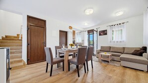 A modern living room with a dining area, a sofa, and a staircase. - Greenwood Retreat With Hot Tub & Sauna, Sveti Martin na Muri, Croatia (Sveti Martin na Muri)