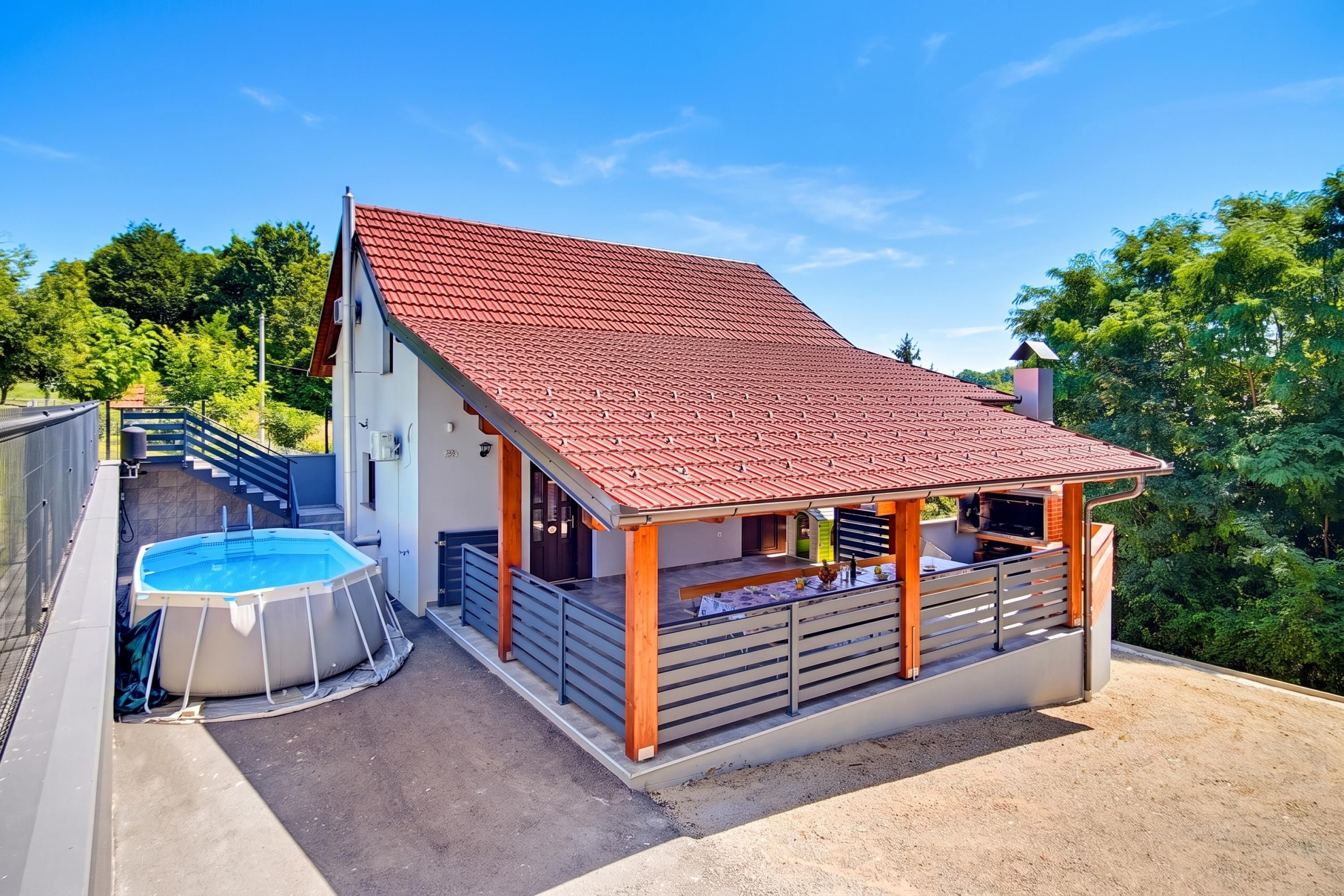 A two-story house with a red-tiled roof, a swimming pool, and a covered patio area.