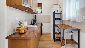 A compact kitchen with wooden cabinets, a built-in stove, and a fruit bowl on the counter. - Greenwood Retreat With Hot Tub & Sauna, Sveti Martin na Muri, Croatia (Sveti Martin na Muri)