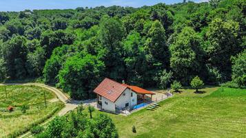 A modern house with a red roof, surrounded by lush greenery and a clear sky.