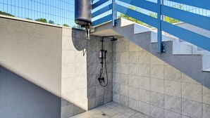 A modern outdoor shower area with a metal water tank, a hose, and a showerhead. - Greenwood Retreat With Hot Tub & Sauna, Sveti Martin na Muri, Croatia (Sveti Martin na Muri)