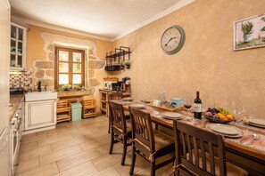A cozy kitchen with stone walls, wooden cabinets, and a dining area set for a meal. - Villa Dalmatia | Luxury Stone Villa with Pool & Tennis, Biograd na Moru, Croatia (Biograd na Moru)
