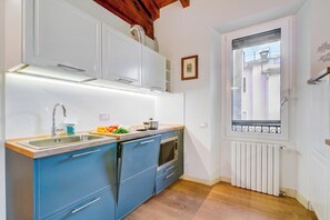 A compact kitchen with a built-in oven, a sink, and a window overlooking a balcony. - Paul | Spacious Central Apart & Garage, Salò, Italy (Salò)