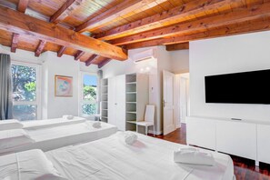 A modern hotel room with a wooden ceiling, a large bed, a TV, and a view of the outdoors. - Paul | Spacious Central Apart & Garage, Salò, Italy (Salò)
