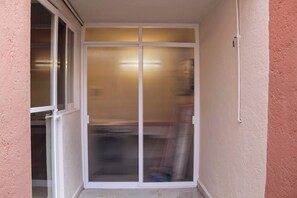Eine Glastür mit vertikalen Jalousien, ein weißer Türrahmen und ein an der Wand befestigter Lichtschalter.