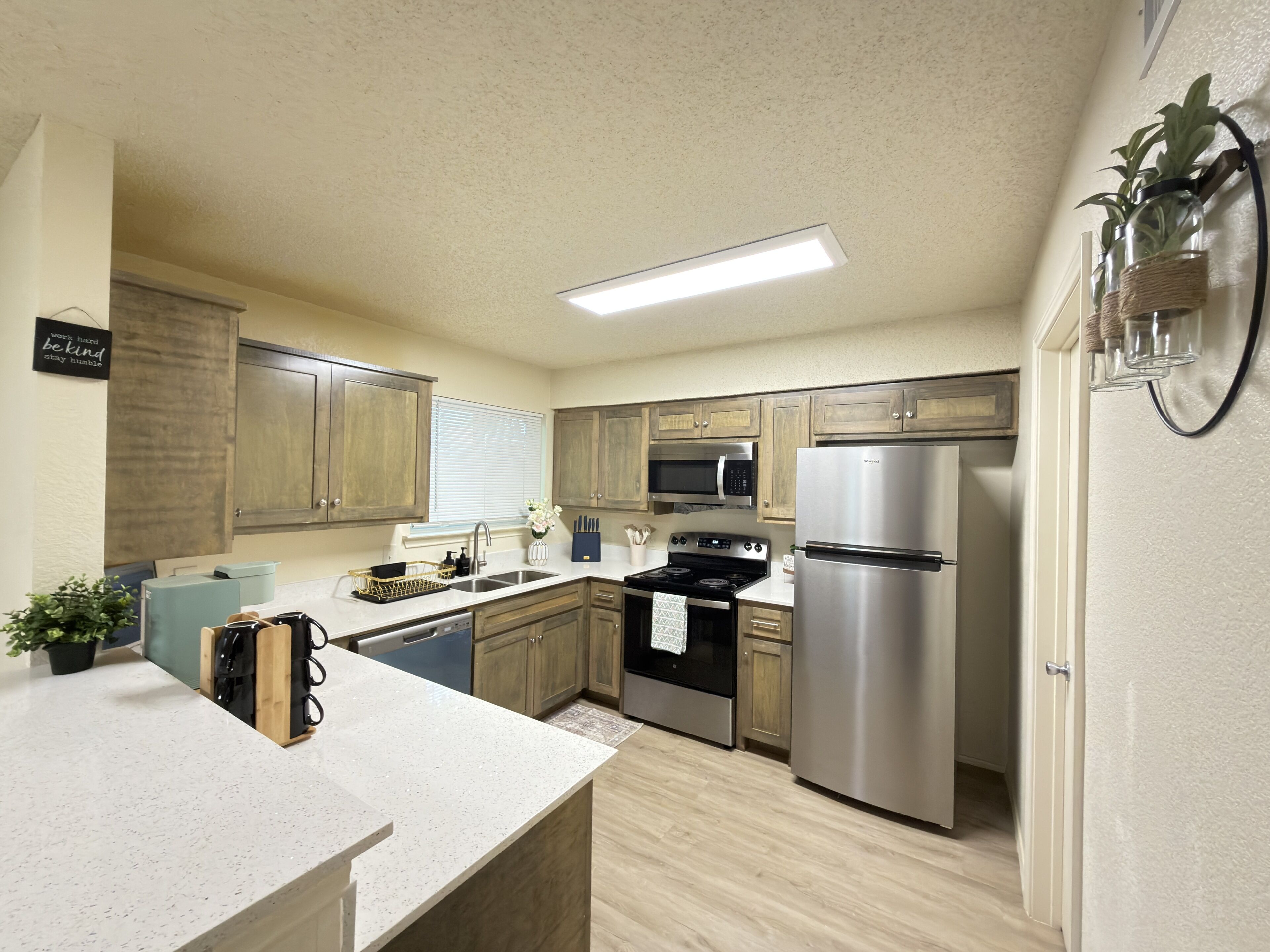 A modern kitchen with wooden cabinets, stainless steel appliances, and a countertop with a sink.