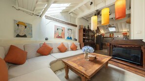 A living room with a sofa, a wooden coffee table, and artwork on the walls. - Villa Hangat by Villa Finder (Badung)