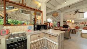 Une cuisine spacieuse équipée d’une cuisinière à gaz, d’un four et d’un four à micro-ondes, un coin repas avec une table et des chaises en bois, et un grand miroir au-dessus du comptoir.