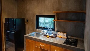 Una cocina compacta con refrigerador integrado, un lavamanos y una ventana con vista a un jardín.