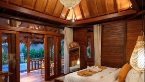 Una habitación de madera con una cama, una ventana y una puerta que da a un espacio exterior.
