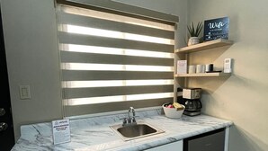 Een kleine keuken met een ingebouwde magnetron, een spoelbak en een kleine koelkast.