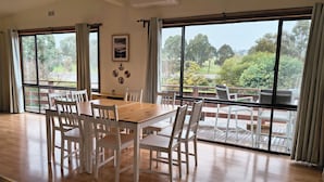 A spacious room with a large dining table and chairs, a balcony with outdoor seating, and large windows offering a view of the outdoors. - Red Gum - enjoy superb views in the heart of Merrijig! Sleeps 9 (Merrijig)