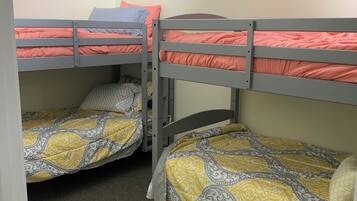 A room with bunk beds, carpeted floor, and a ceiling light fixture.