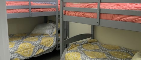 A room with bunk beds, carpeted floor, and a ceiling light fixture.