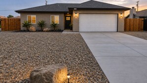 Ein Bungalow mit Garage, einem Schotterweg und einem großen Felsen.