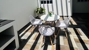 A patio with a round table and four chairs, a potted plant, and a window. - Bohemian Zen House Entire home in Mazatlán, Mexico (Mazatlán)