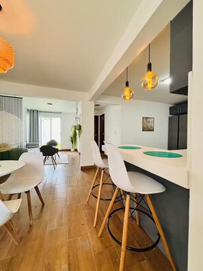 Eine moderne Küche mit weißen Schränken, einem schwarzen Kühlschrank und einer Pendelleuchte.